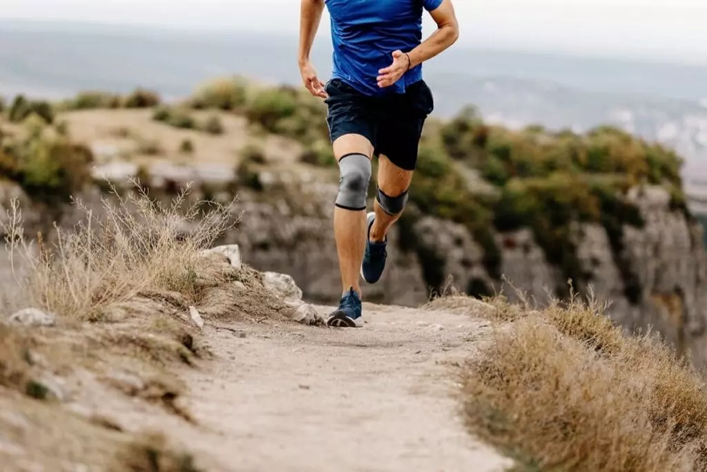 Person running on trail with knee brace